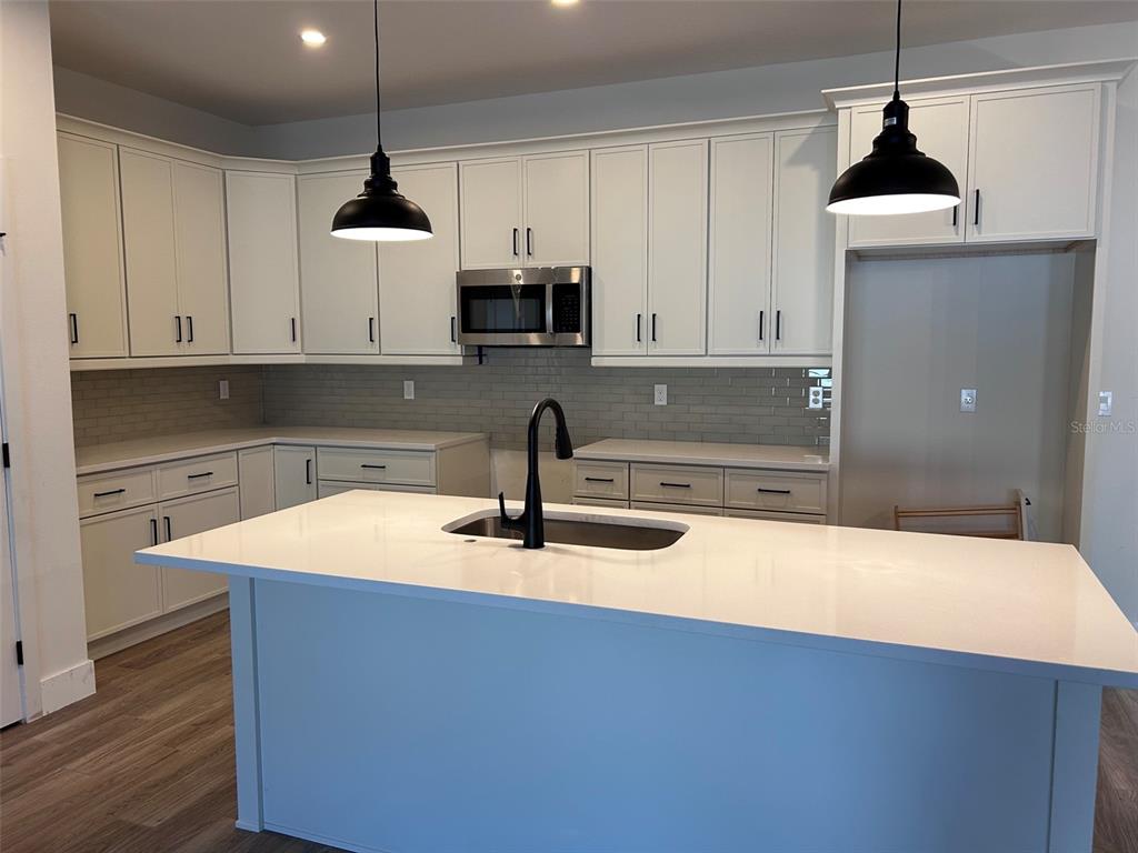 A modern kitchen features white cabinetry, a large center island, and black pendant lighting — 340 KIMBLE AVENUE, OVIEDO, FL