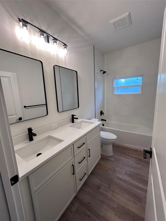 A modern bathroom features a double vanity with black fixtures, two mirrors, and a tub-shower — 340 KIMBLE AVENUE, OVIEDO, FL