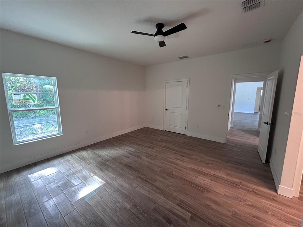 An empty bedroom features wood-look tile flooring, a ceiling fan, and two doorways — 340 KIMBLE AVENUE, OVIEDO, FL