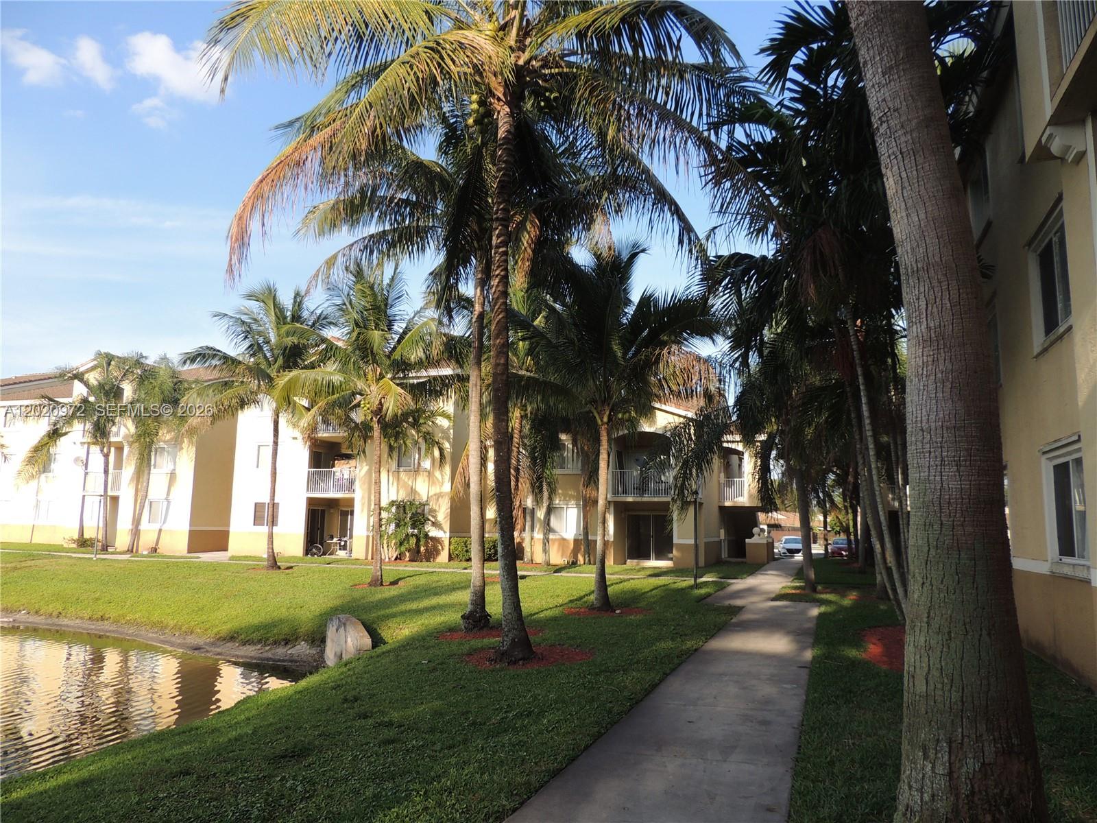A hallway with beige walls, tiled flooring, a ceiling light, and several white doors — 2600 S University Dr # 103, Davie FL 33328, DAVIE, FL