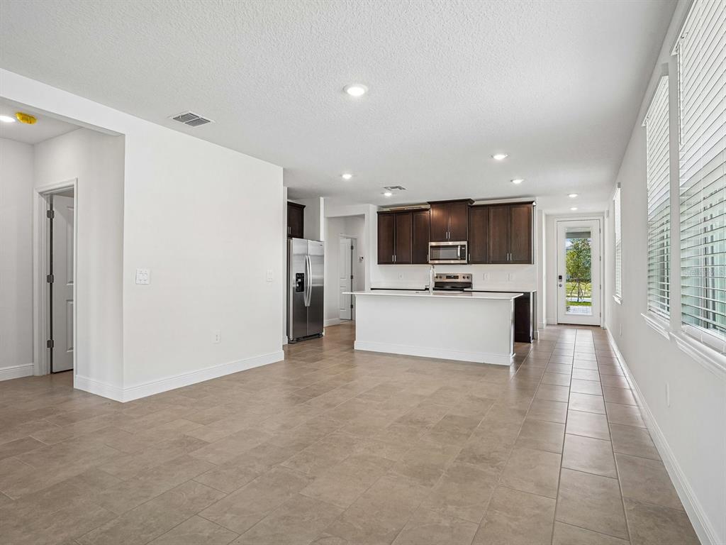 An open-concept kitchen features dark wood cabinets, a white island, and tile flooring — 3389 LINGER LANE, LAKE HAMILTON, FL