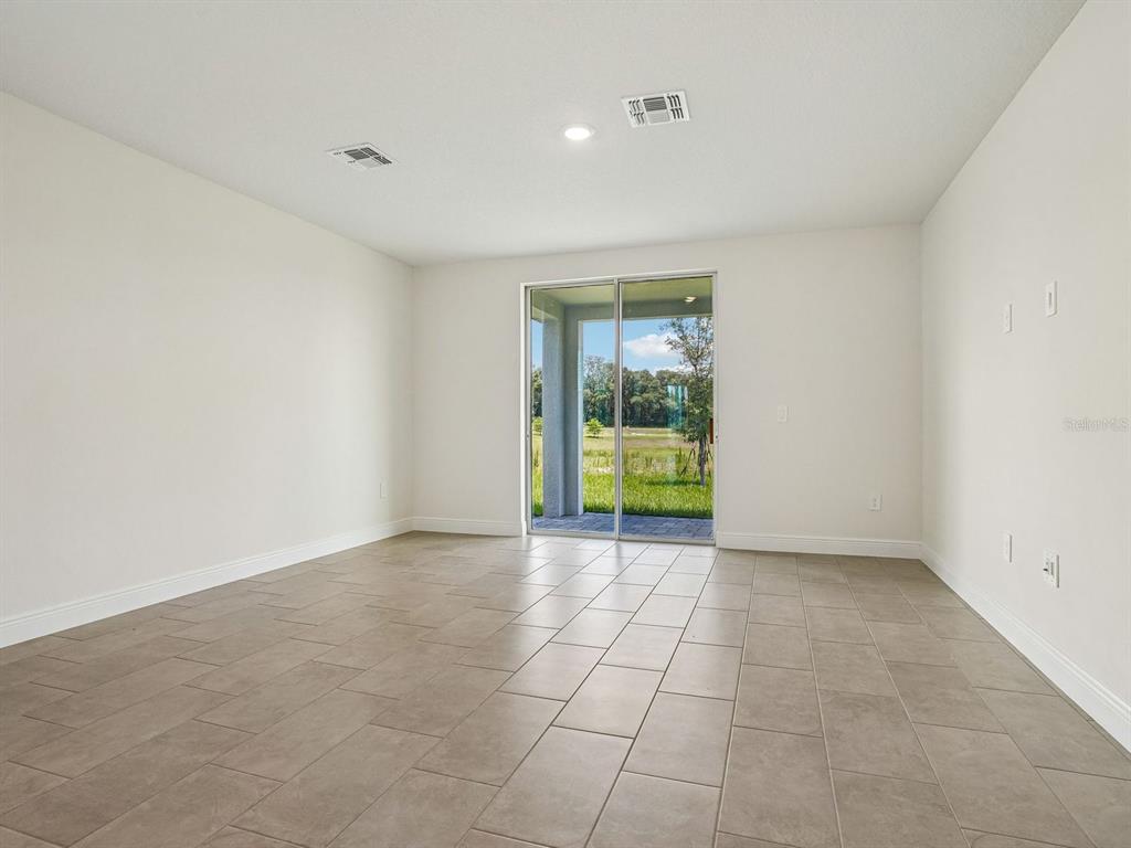 An empty room with light-colored walls, tile flooring, and a sliding glass door to a patio — 3389 LINGER LANE, LAKE HAMILTON, FL
