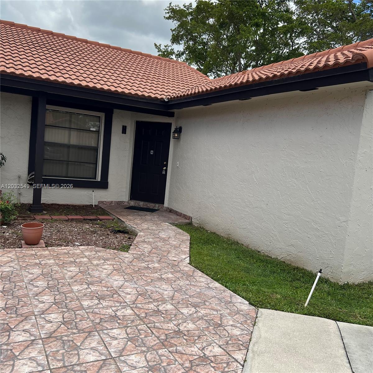 The exterior of a house features a tiled roof, a black front door, and stone-patterned pavers — 15272 SW 46th Ln # 66, Miami FL 33185, MIAMI, FL