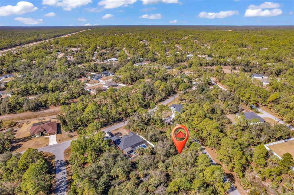 An aerial view shows a house with a pool surrounded by dense forest and roads — DE BRITA ROAD, NORTH PORT, FL