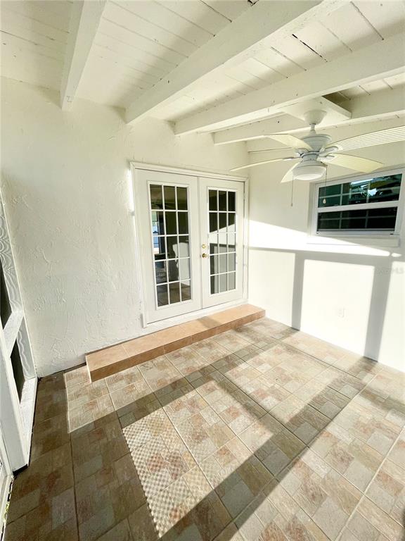 A sunroom features tiled flooring, a ceiling fan, and white French doors leading inside — 4608 S HESPERIDES STREET, TAMPA, FL