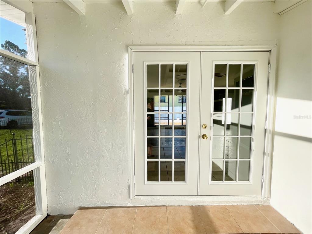 A white-walled screened porch features French doors leading into a tiled interior room — 4608 S HESPERIDES STREET, TAMPA, FL