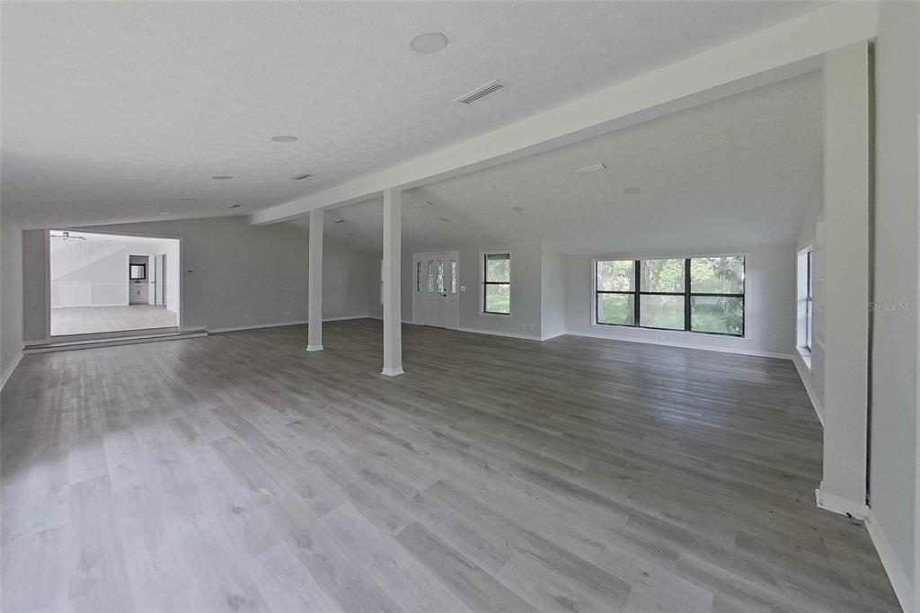 A spacious, open-concept living area features light gray wood-look flooring and white support columns — 6249 LAKE DRIVE, STARKE, FL