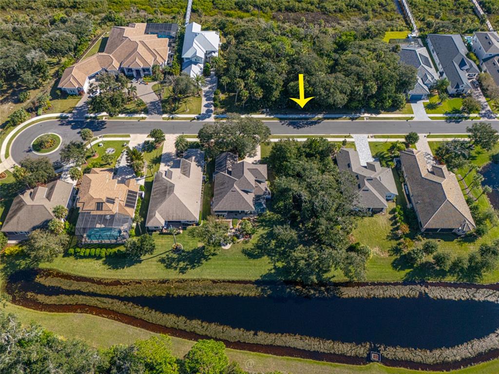 An aerial view shows a vacant residential lot marked by a yellow arrow near water — 63 N RIVERWALK DRIVE, PALM COAST, FL