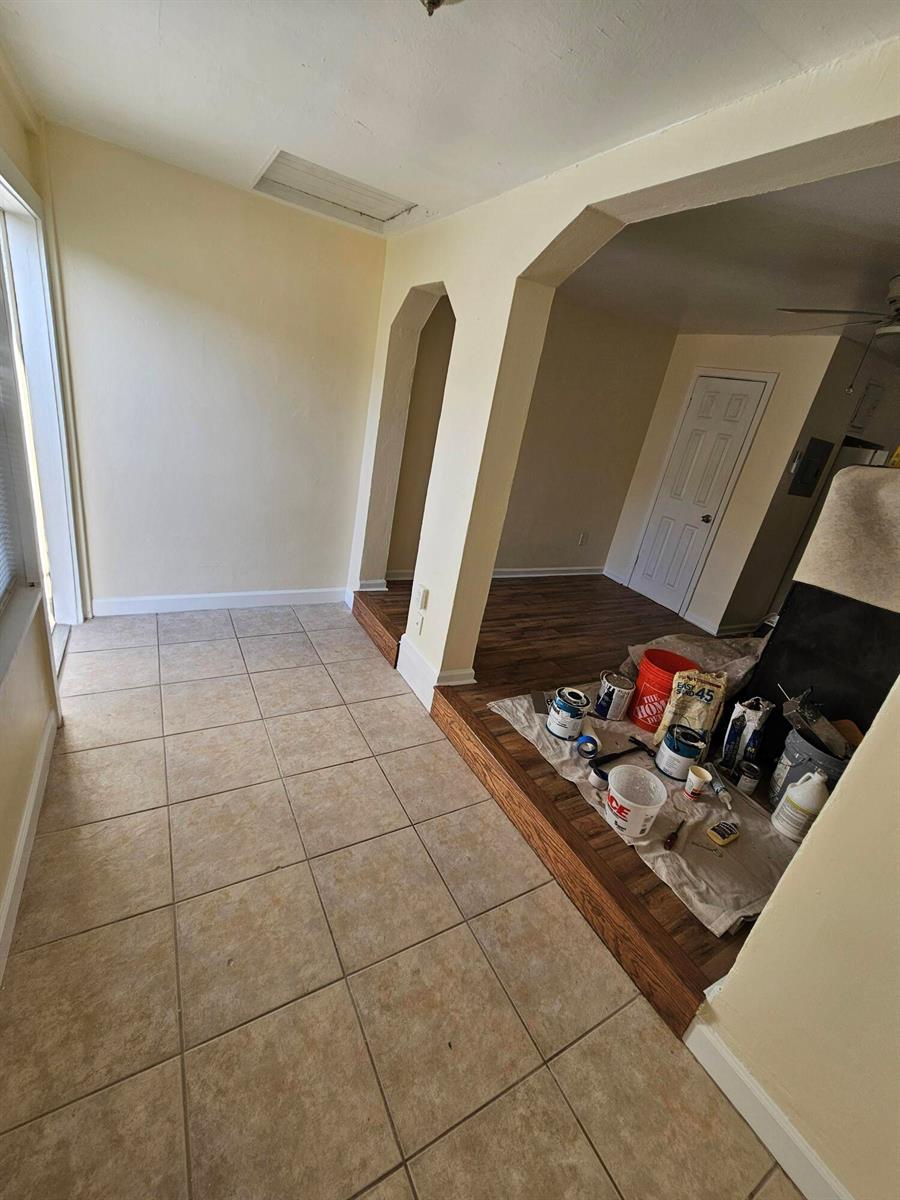 A tiled sunroom leads into a living area with wood flooring and construction supplies — 115 E Palm Street E # 117, Lantana FL 33462, LANTANA, FL