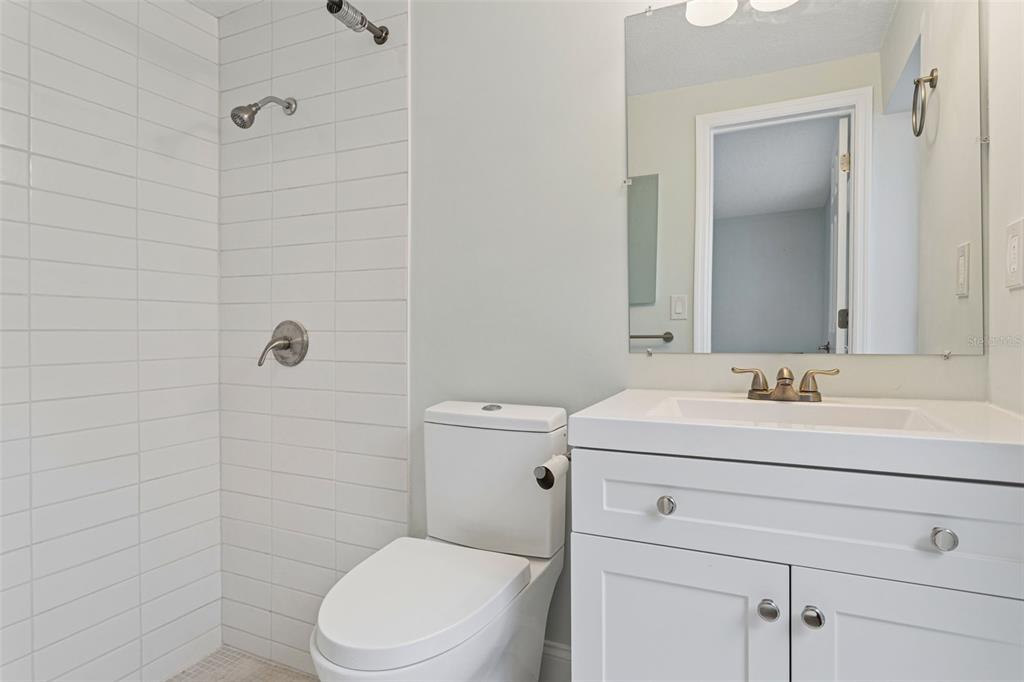 A bathroom features a white vanity, a toilet, and a tiled walk-in shower — 3115 PALAMORE DRIVE, HOLIDAY, FL