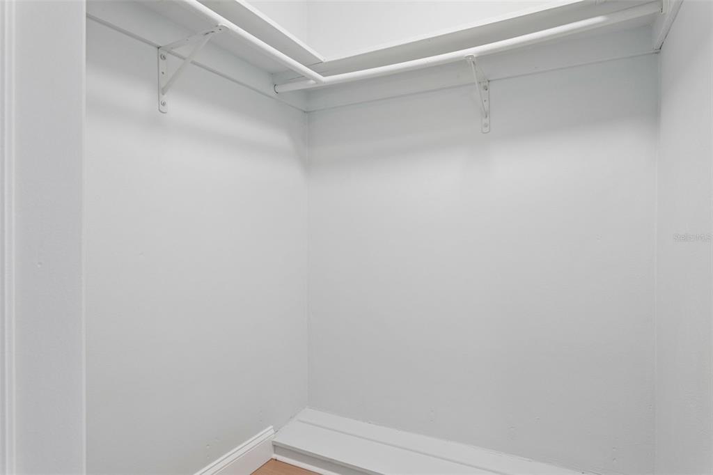 A white walk-in closet features a corner shelf and a metal hanging rod — 3115 PALAMORE DRIVE, HOLIDAY, FL