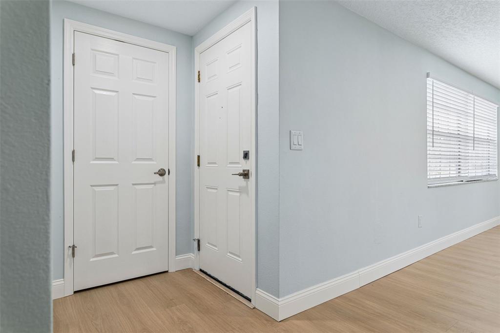 An interior view shows two white doors, light-colored wood flooring, and a window with blinds — 3115 PALAMORE DRIVE, HOLIDAY, FL