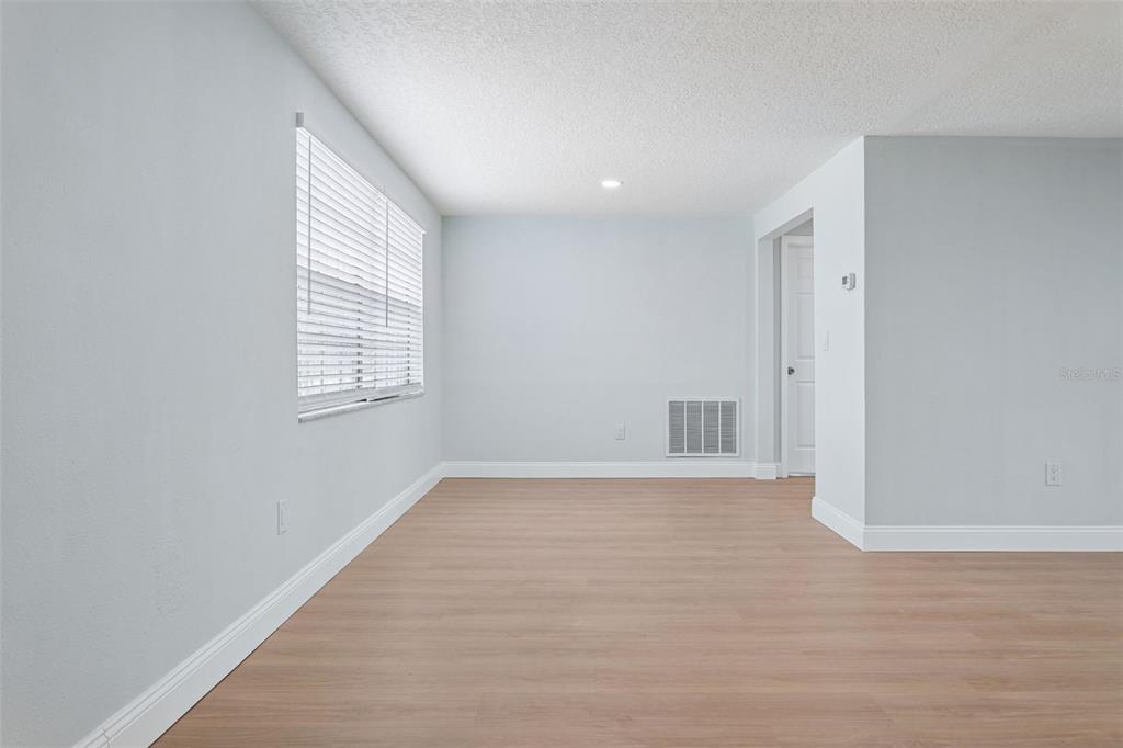 An empty room with light wood-look flooring, white walls, and a window with blinds — 3115 PALAMORE DRIVE, HOLIDAY, FL