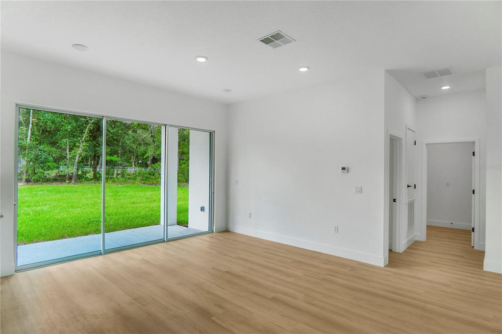 A bright living room features light wood flooring, white walls, and large sliding glass doors — 8383 N IBSEN DRIVE, CITRUS SPRINGS, FL