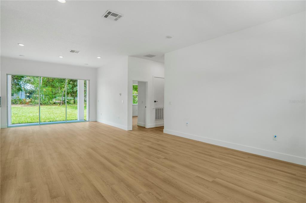 An empty room with light wood-look flooring, white walls, and large sliding glass doors — 8383 N IBSEN DRIVE, CITRUS SPRINGS, FL