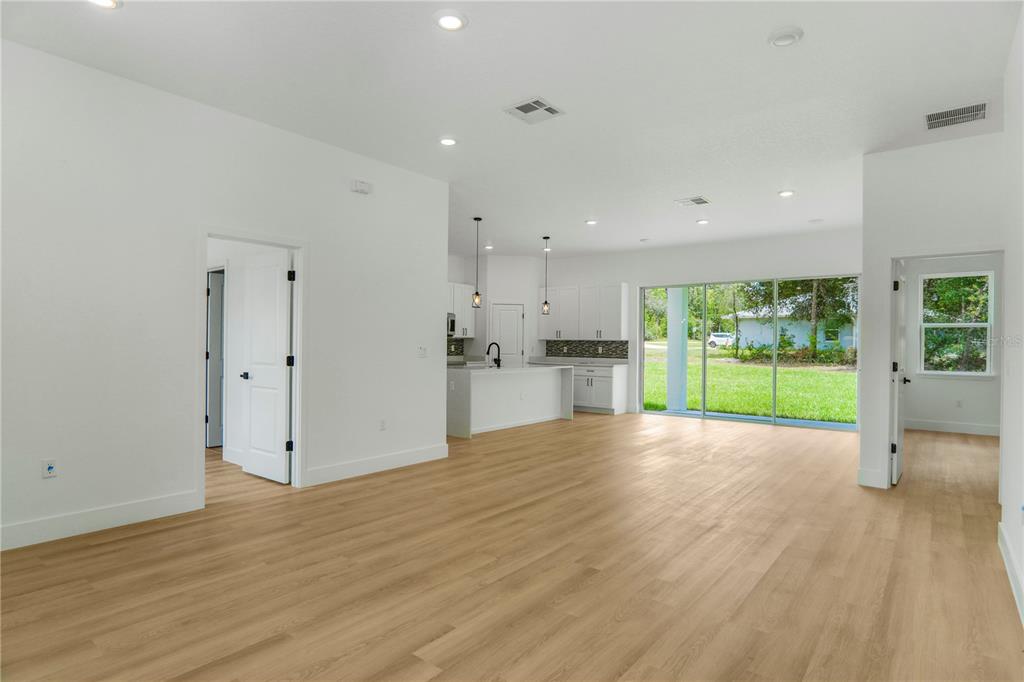 An open-concept living area features light wood-look flooring, white walls, and a kitchen with island — 8383 N IBSEN DRIVE, CITRUS SPRINGS, FL