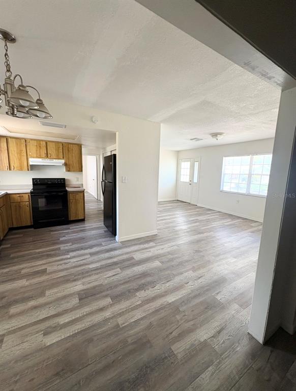 A kitchen with wood cabinets and a black stove opens into a living area — 8151 HIXTON DRIVE, PORT RICHEY, FL