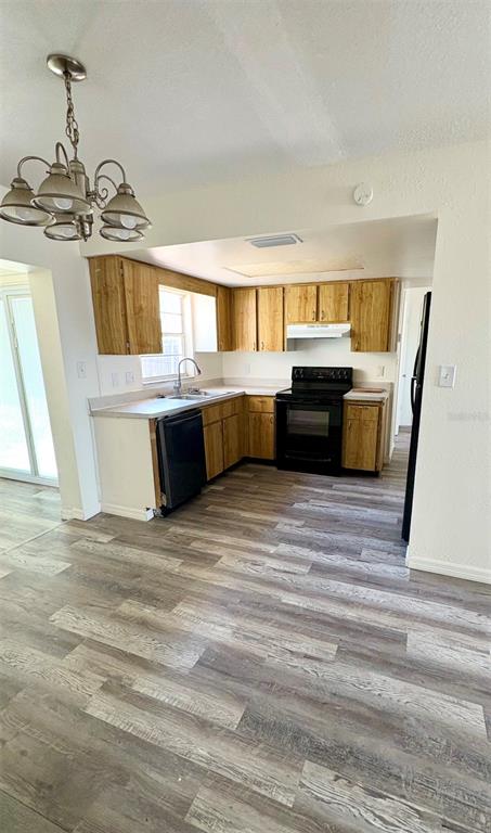 A kitchen features wood cabinets, stainless steel appliances, and light-colored wood-look flooring — 8151 HIXTON DRIVE, PORT RICHEY, FL