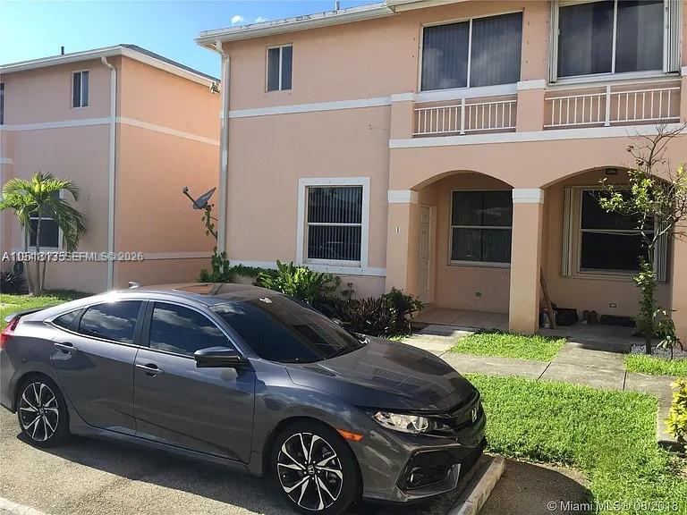 A gray sedan is parked in front of a two-story peach-colored residential building — 885 NE 213th Ter # 2, Miami FL 33179, MIAMI, FL
