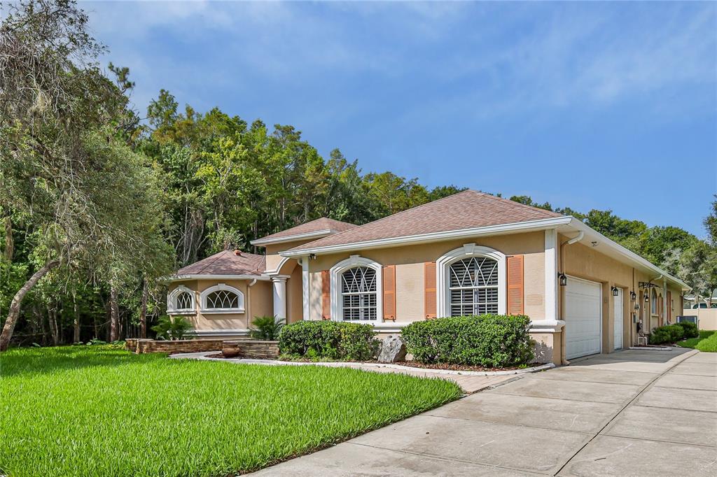 A paved walkway leads to the arched entryway of a tan house with white columns — 11644 PARABLE COURT, NEW PORT RICHEY, FL