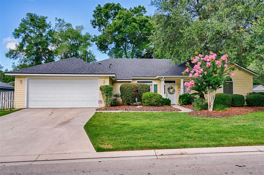 A single-story yellow house with a two-car garage and a blooming crape myrtle tree — 6618 SW 83RD TERRACE, GAINESVILLE, FL