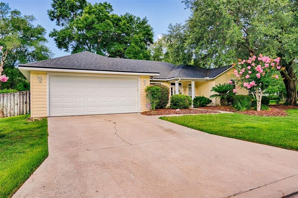 A single-story house with a yellow exterior, a two-car garage, and a concrete driveway — 6618 SW 83RD TERRACE, GAINESVILLE, FL