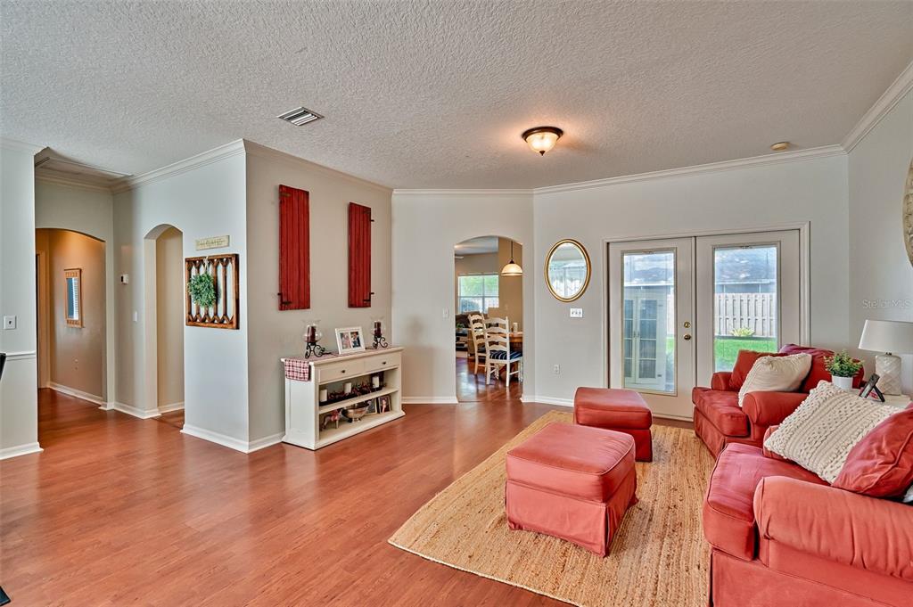 A living room features hardwood floors, red furniture, and a doorway leading to a dining area — 6618 SW 83RD TERRACE, GAINESVILLE, FL