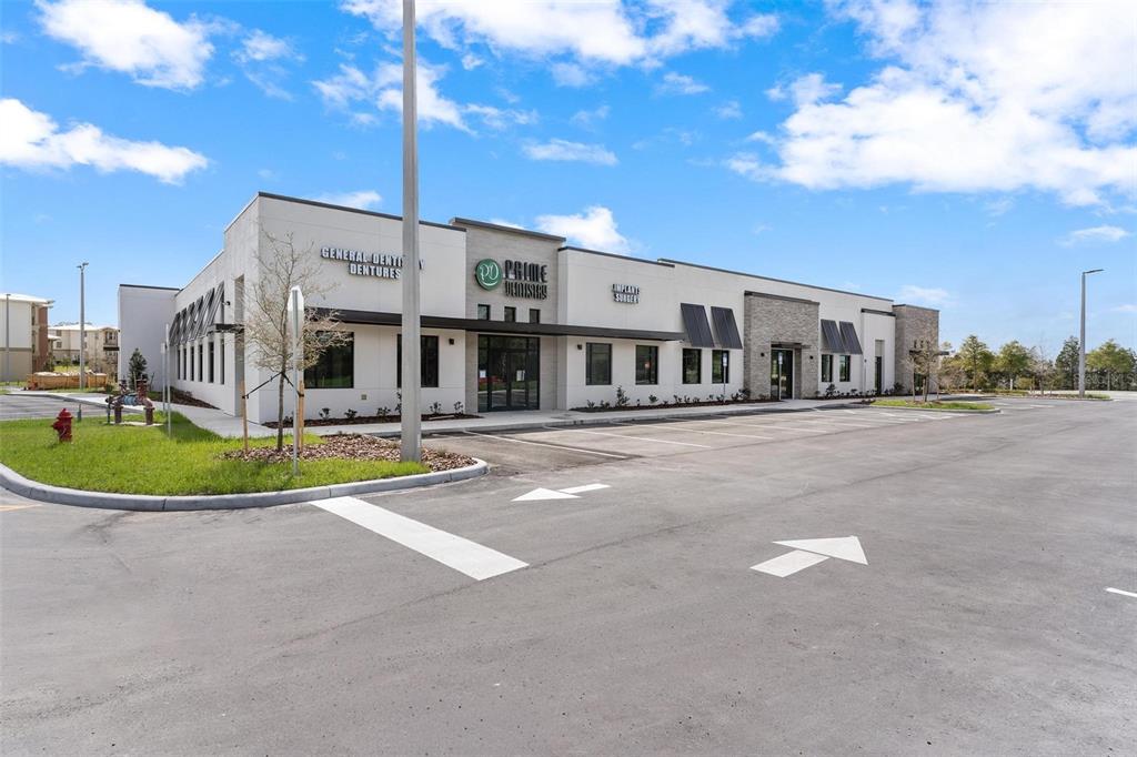 A modern, single-story commercial building with a parking lot and dental office signage — 10941 NE 89TH DRIVE, THE VILLAGES, FL