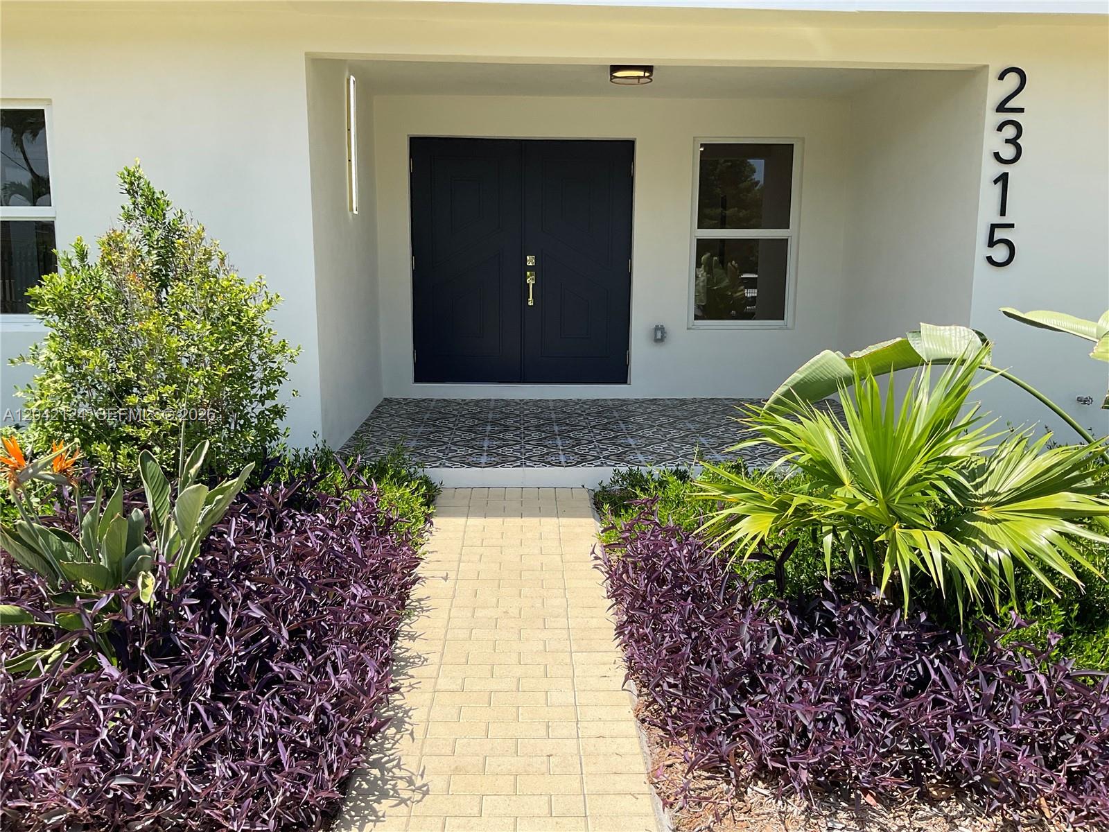 A paved walkway leads to a covered entryway with double doors and patterned tile flooring — 2315 NW 3rd St, Miami FL 33125, MIAMI, FL