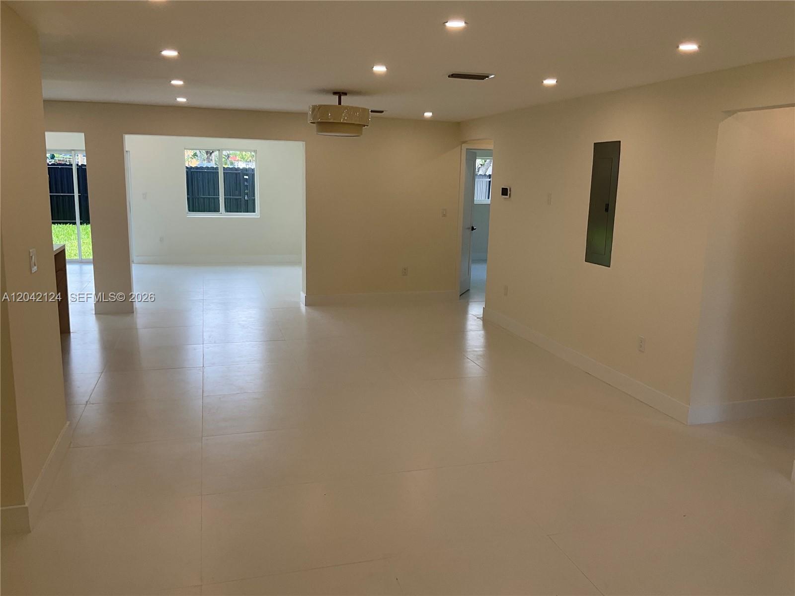 An open-concept living area features white tile flooring, recessed lighting, and a central chandelier — 2315 NW 3rd St, Miami FL 33125, MIAMI, FL