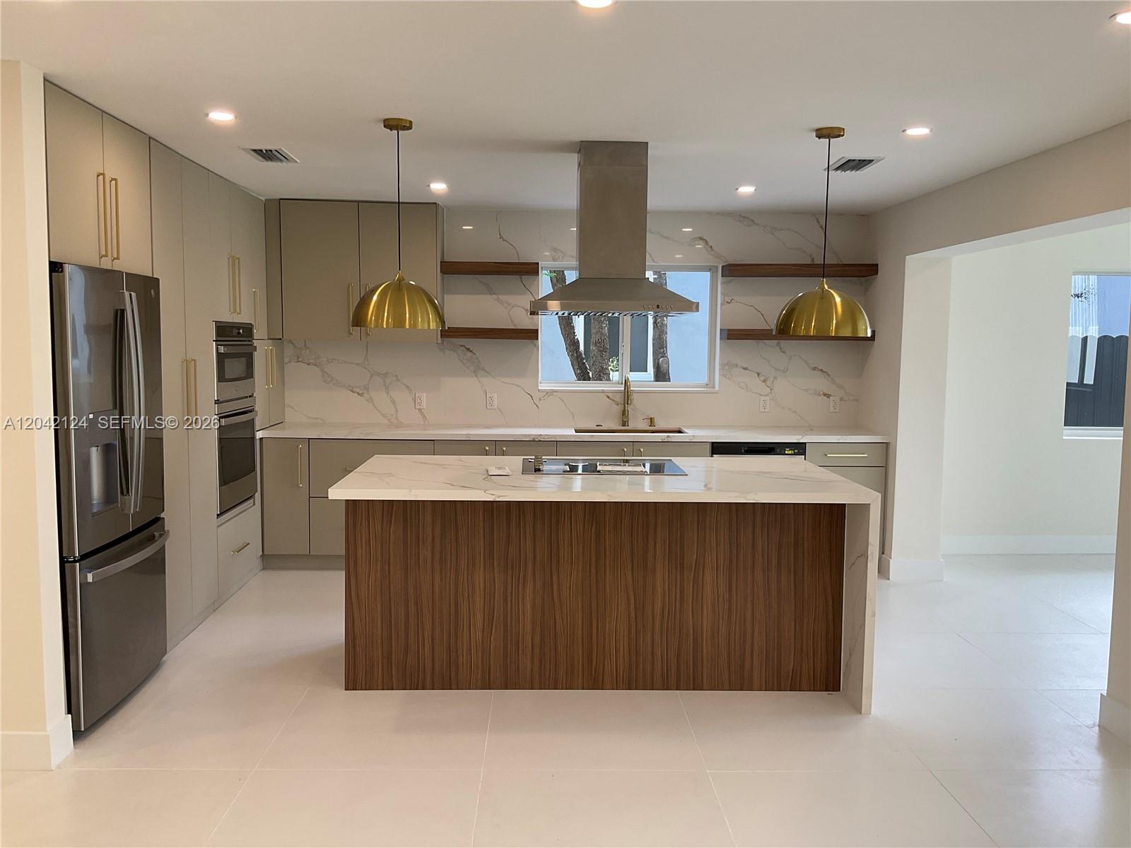 A modern kitchen features a wood-paneled island, marble countertops, and gold pendant lighting — 2315 NW 3rd St, Miami FL 33125, MIAMI, FL