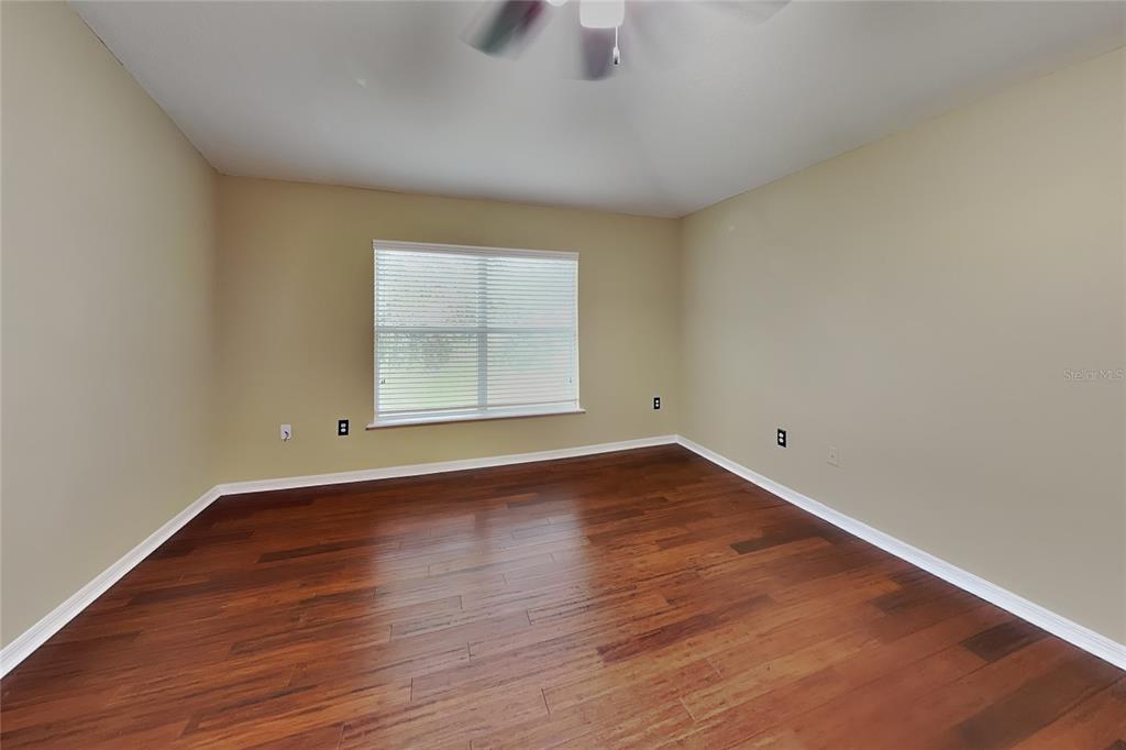 An empty room features beige walls, dark hardwood flooring, and a single window with blinds — 1952 ALAMBRA CIRCLE, APOPKA, FL