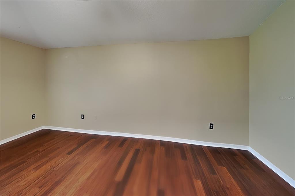 An empty room features light-colored walls, dark wood flooring, and three black electrical outlets — 1952 ALAMBRA CIRCLE, APOPKA, FL