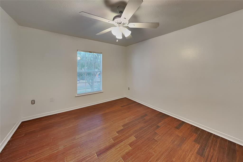 An empty bedroom features white walls, a ceiling fan, and dark wood flooring — 1952 ALAMBRA CIRCLE, APOPKA, FL