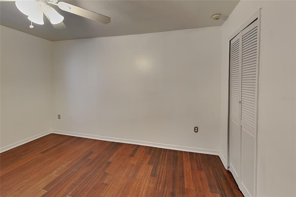 An empty bedroom features white walls, dark wood flooring, a ceiling fan, and a closet — 1952 ALAMBRA CIRCLE, APOPKA, FL