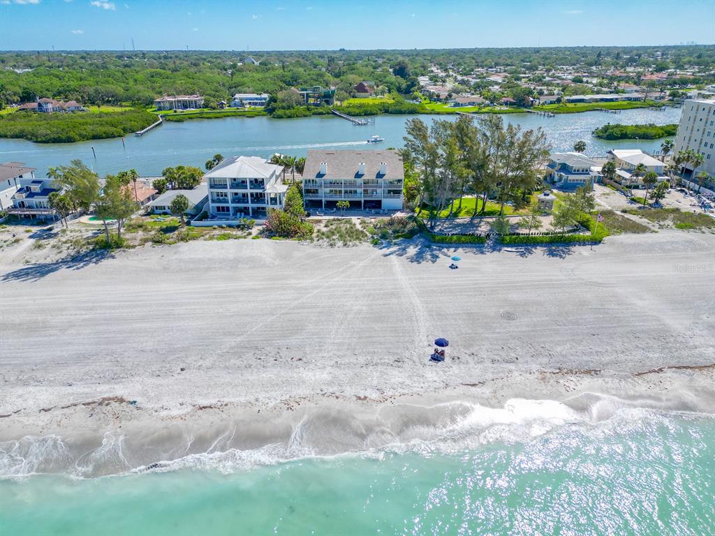 An aerial view shows two beachfront buildings situated between a sandy beach and a waterway — 20204 GULF BOULEVARD UNIT 3, INDIAN SHORES, FL
