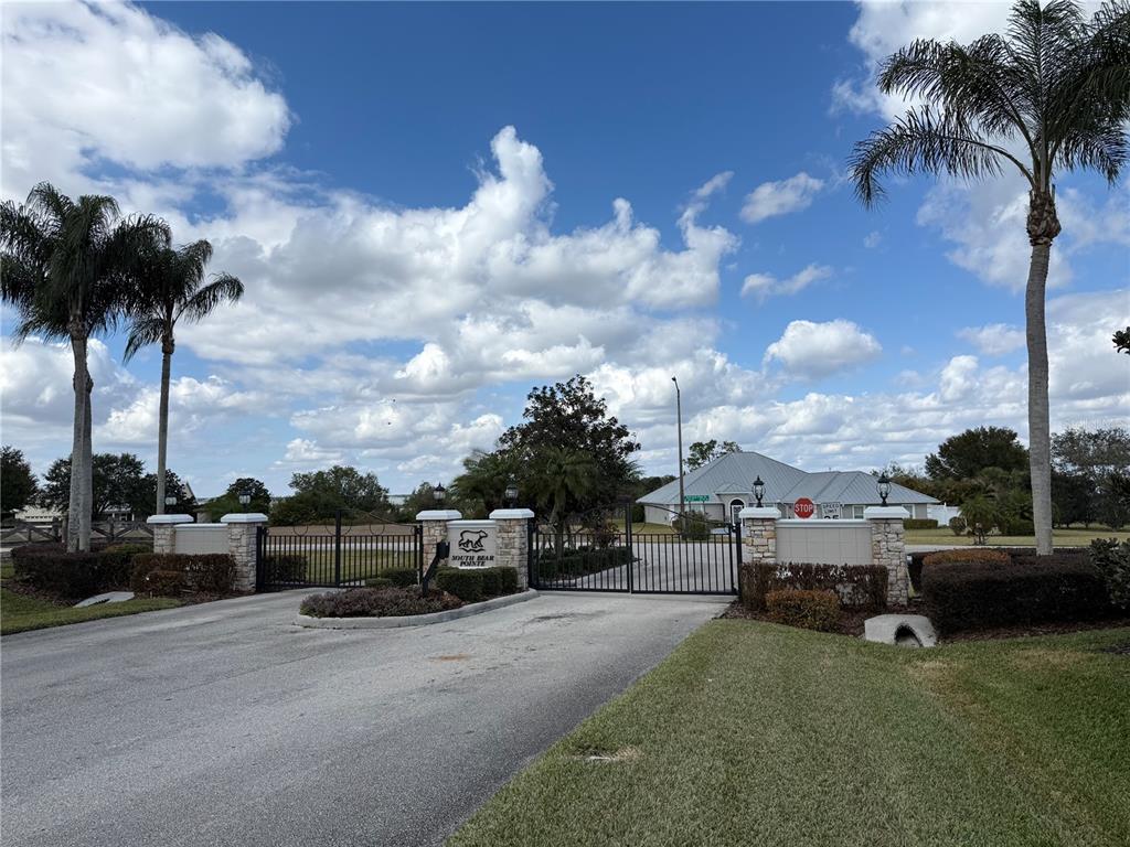 The gated entrance to a residential community features stone pillars, palm trees, and a sign — 186 S BEAR POINTE DRIVE, LAKE PLACID, FL