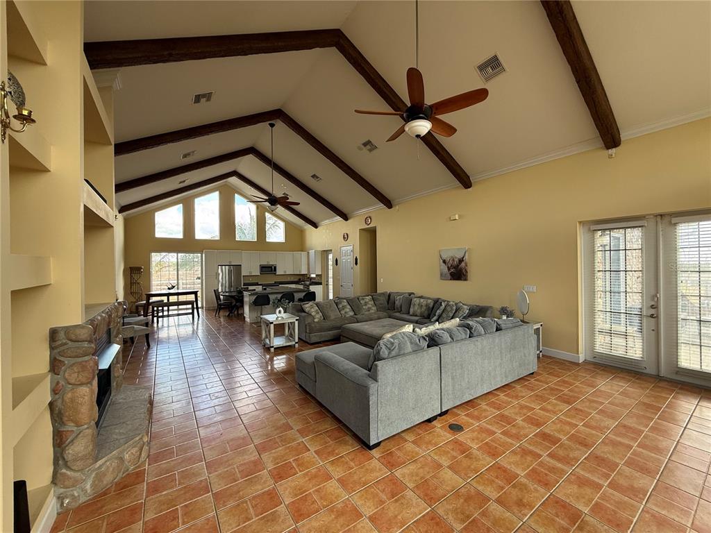 A spacious open-concept living room features vaulted ceilings with exposed beams and tile flooring — 186 S BEAR POINTE DRIVE, LAKE PLACID, FL