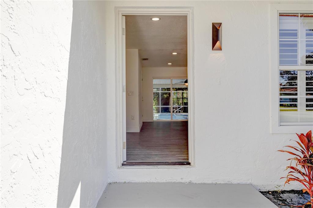 A view through an open doorway into a home interior with a backyard pool visible — 2261 S FLAGLER AVENUE, FLAGLER BEACH, FL