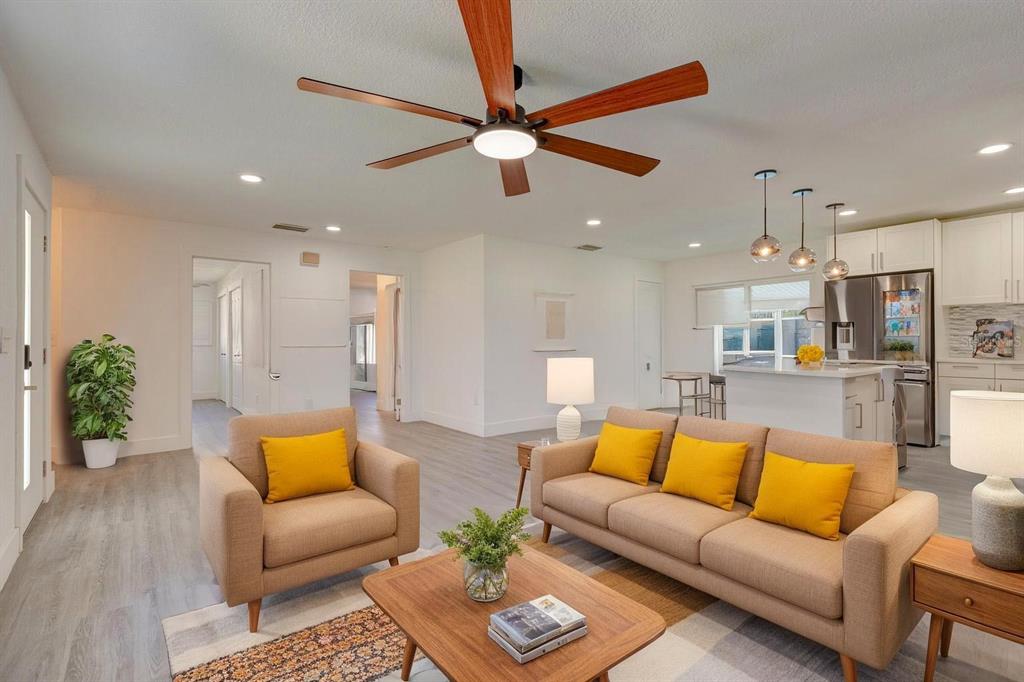 A living room with a ceiling fan, beige sofa, armchair, and an open kitchen background — 2261 S FLAGLER AVENUE, FLAGLER BEACH, FL