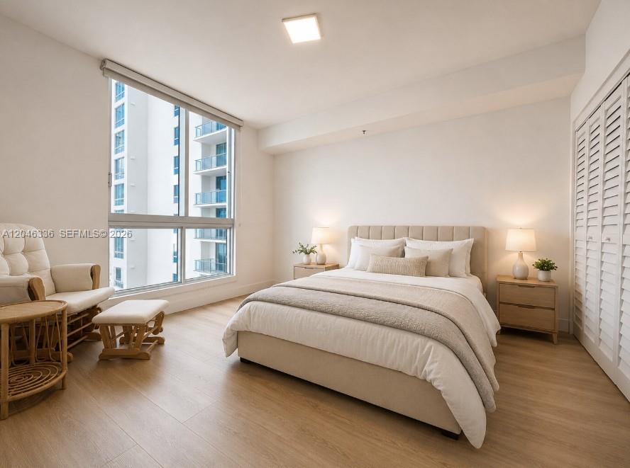 A bedroom features a bed, two nightstands, a chair with an ottoman, and large windows — 300 S Biscayne Blvd # 1503, Miami FL 33131, MIAMI, FL