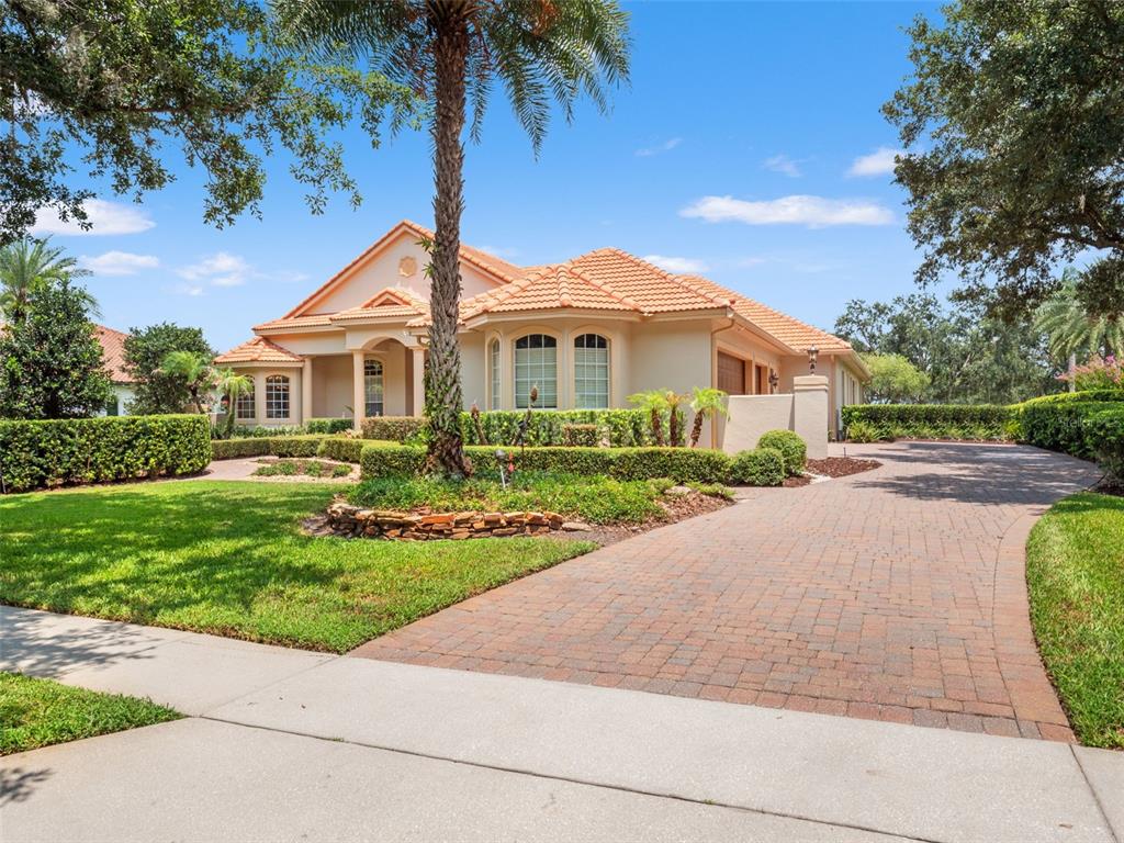 A single-story house with a tile roof, stucco exterior, and a brick paver driveway — 32516 HAWKS LAKE LANE, SORRENTO, FL