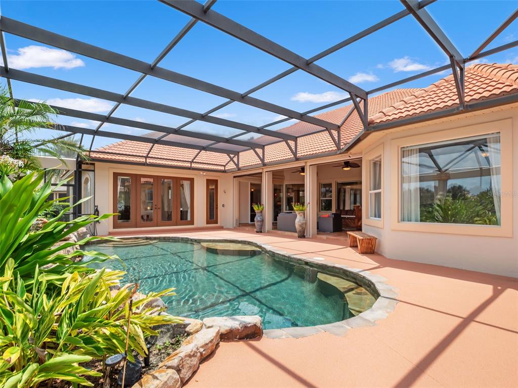 A screened-in patio features a swimming pool with rock accents and a tiled roof house — 32516 HAWKS LAKE LANE, SORRENTO, FL