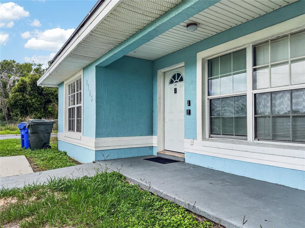 A light blue house exterior features a front porch, a white door, and two windows — 1155 W 5TH STREET, LAKELAND, FL