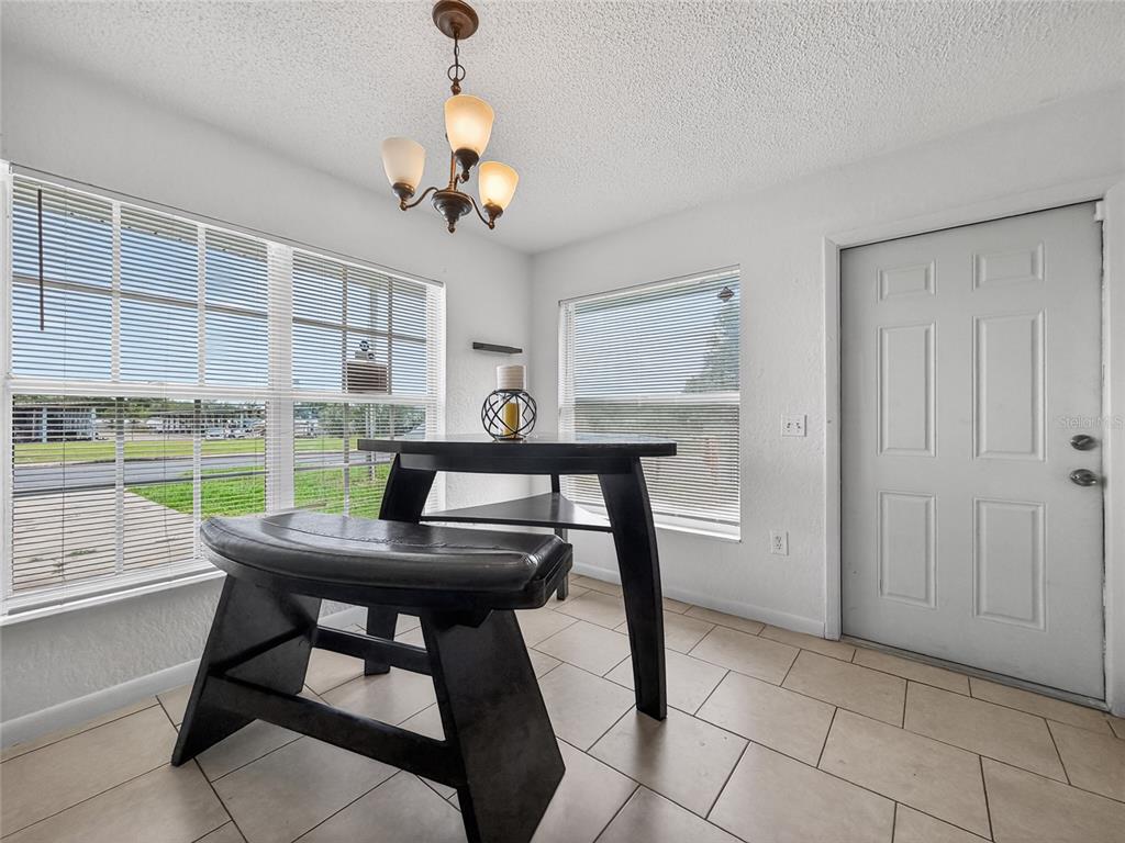 A dining nook features a dark wood table and bench, tile flooring, and a chandelier — 1155 W 5TH STREET, LAKELAND, FL