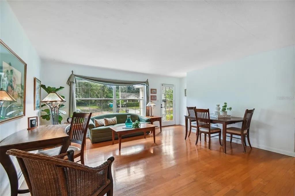 A living and dining area with hardwood floors, a green sofa, and a large window — 1500 E RIDGEWOOD STREET, ORLANDO, FL