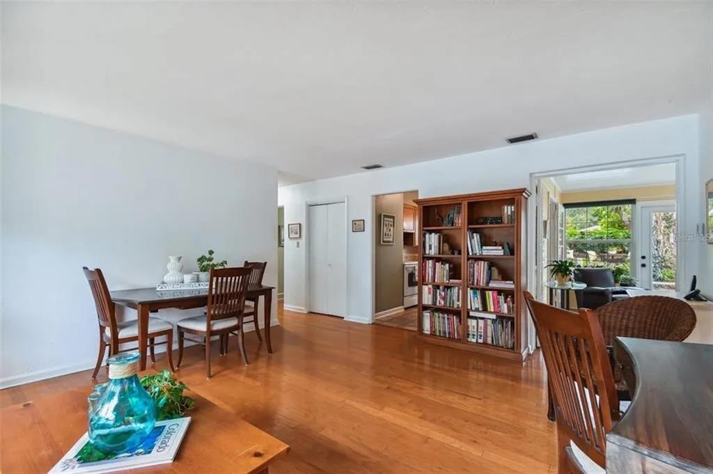 A dining area with hardwood floors, a wooden bookshelf, and a view into a sunroom — 1500 E RIDGEWOOD STREET, ORLANDO, FL
