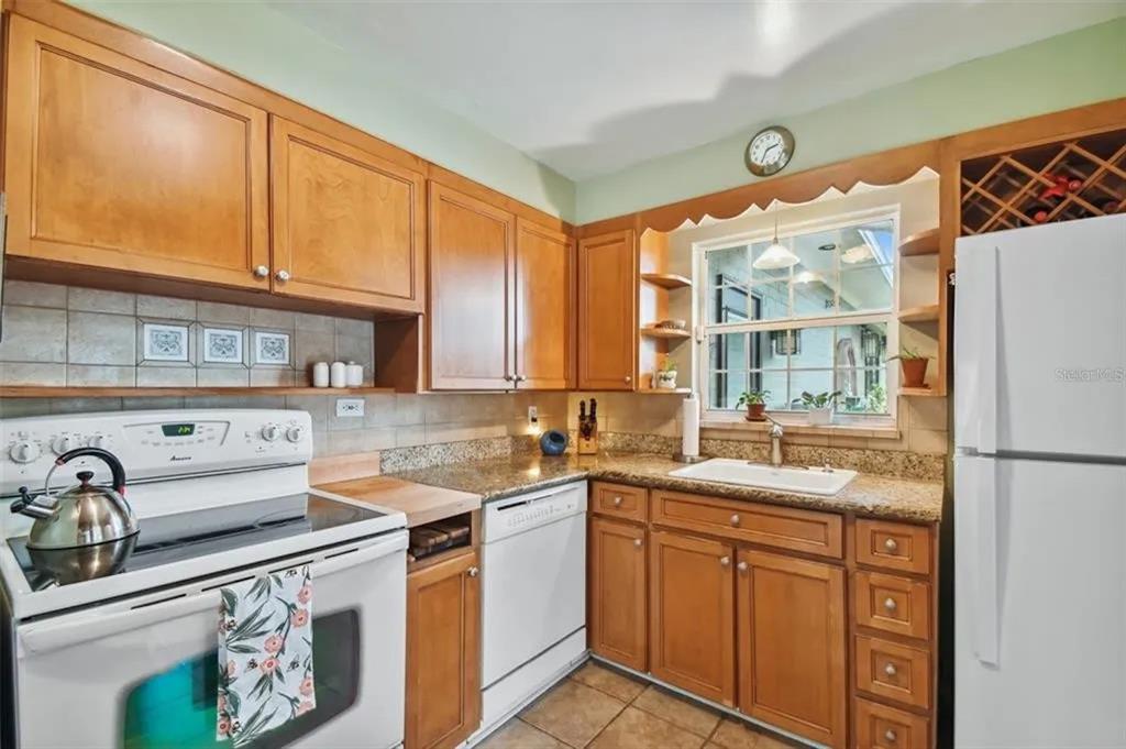 A kitchen with wood cabinets, granite countertops, white appliances, and a window above the sink — 1500 E RIDGEWOOD STREET, ORLANDO, FL