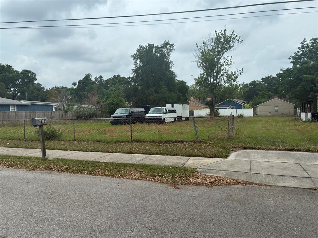 A fenced, vacant grassy lot sits along a residential street with two parked vans — 2726 S BROWN AVENUE, ORLANDO, FL