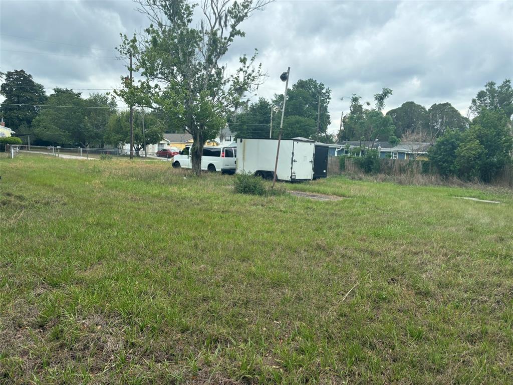 A grassy vacant lot features a white van and a trailer parked under a tree — 2726 S BROWN AVENUE, ORLANDO, FL